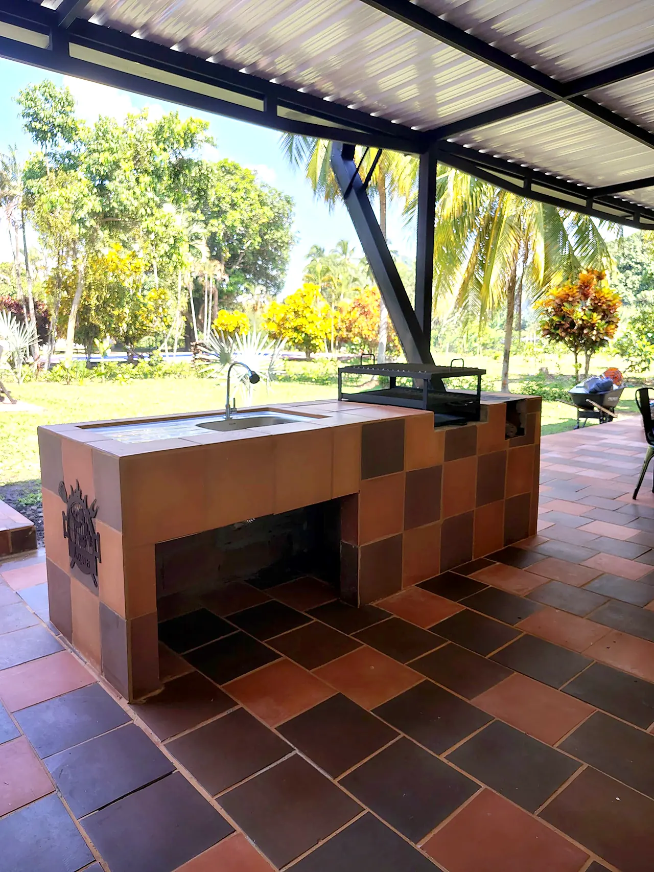 Parrilla BBQ de ladrillo bajo la terraza con vista a la piscina