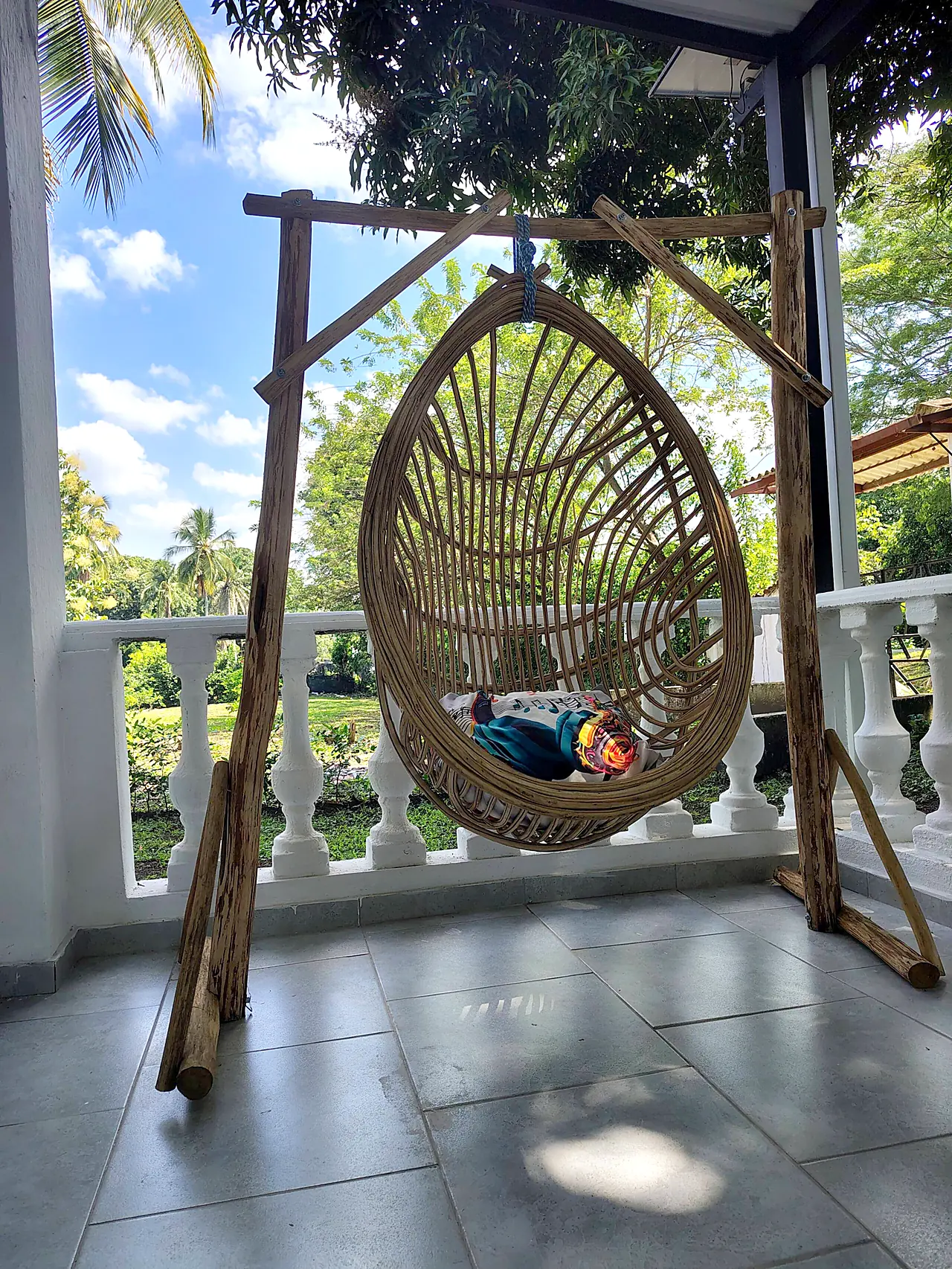 Silla colgante tejida en la terraza con vista al jardín